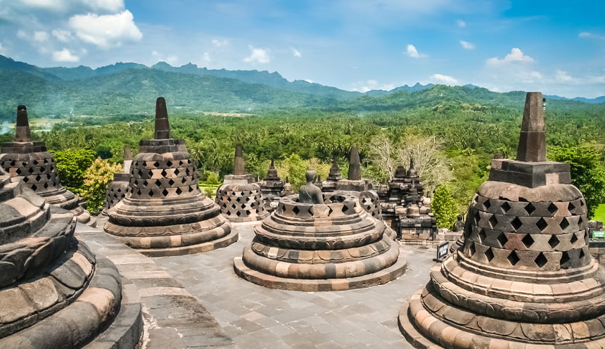 Vista da uno degli ultimi livelli del templio con diverse stupa in primo piano e la foresta sullo sfondo