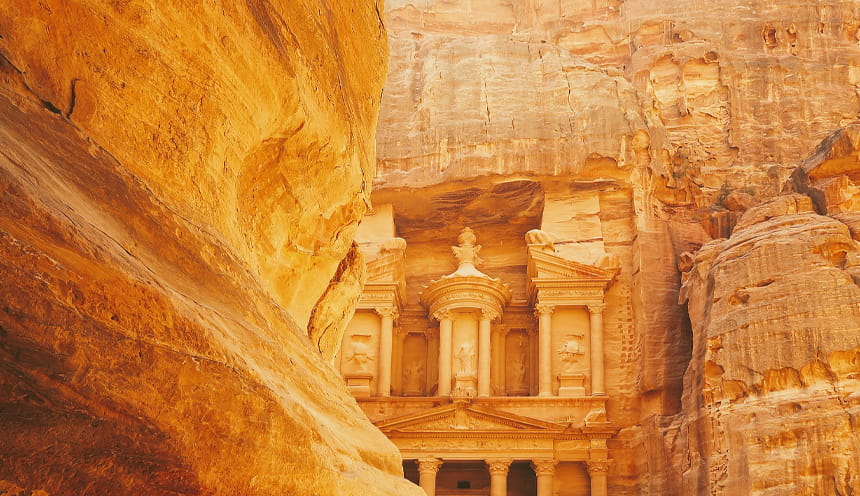 La facciata di un tempio scolpita nella roccia rossa-arancio del deserto.